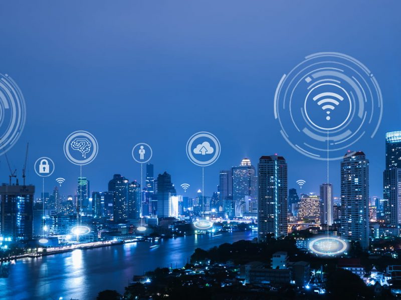 A city at night with icons for the connections through the Internet of Things