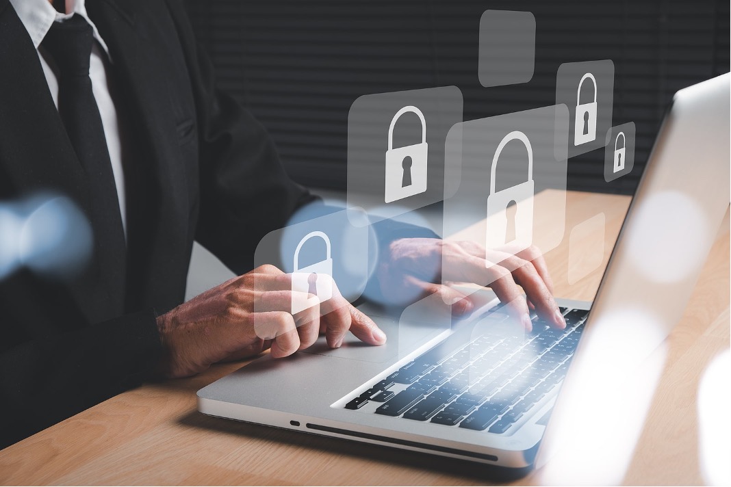 Man’s hand typing on laptop computer with padlock security icons for data privacy